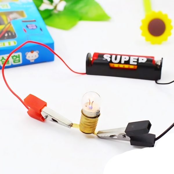 Small electrical setup with a light bulb, clips, and batteries on a white surface.