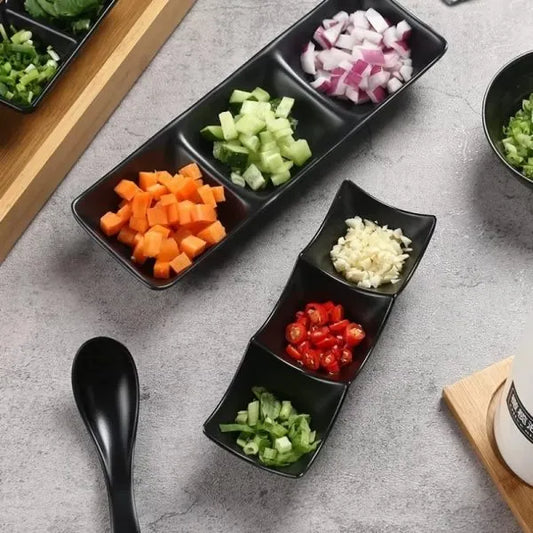 Black divided plate with chopped vegetables on a gray surface