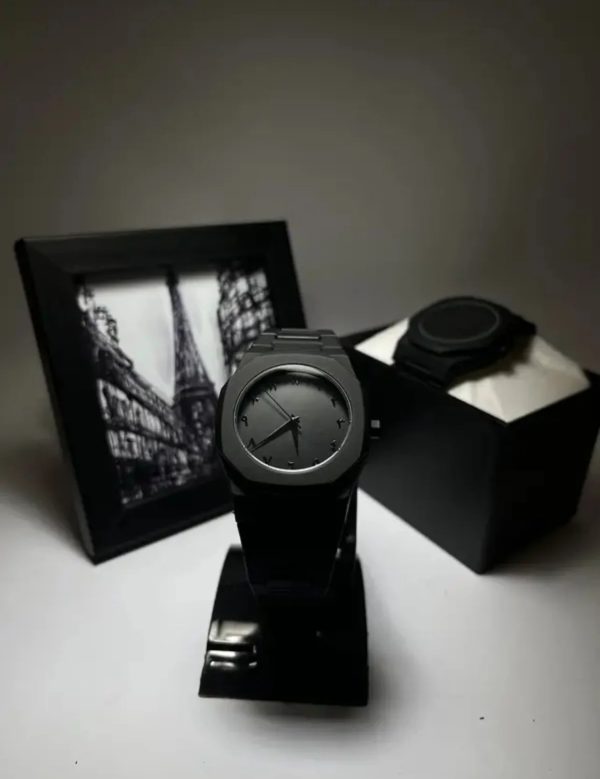 Black watch on a stand with a black box and photo frame in the background