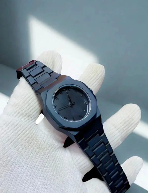Black wristwatch on a white glove against a gray background