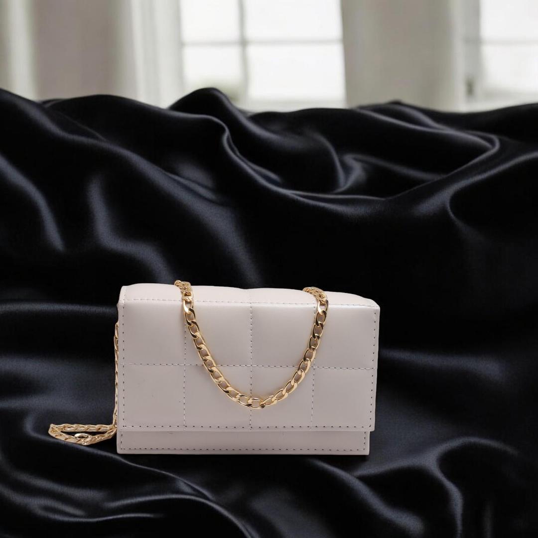 White handbag with a gold chain on a black satin background