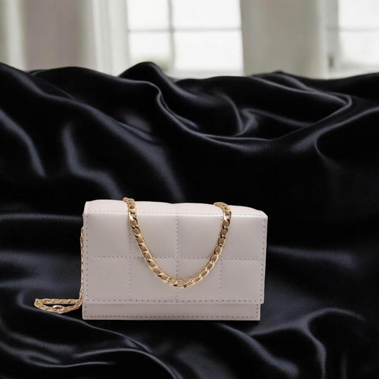 White handbag with a gold chain on a black satin background