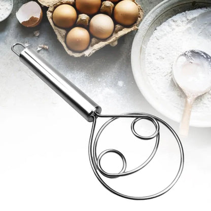 Metallic kitchen tool on a surface with eggs and flour in the background