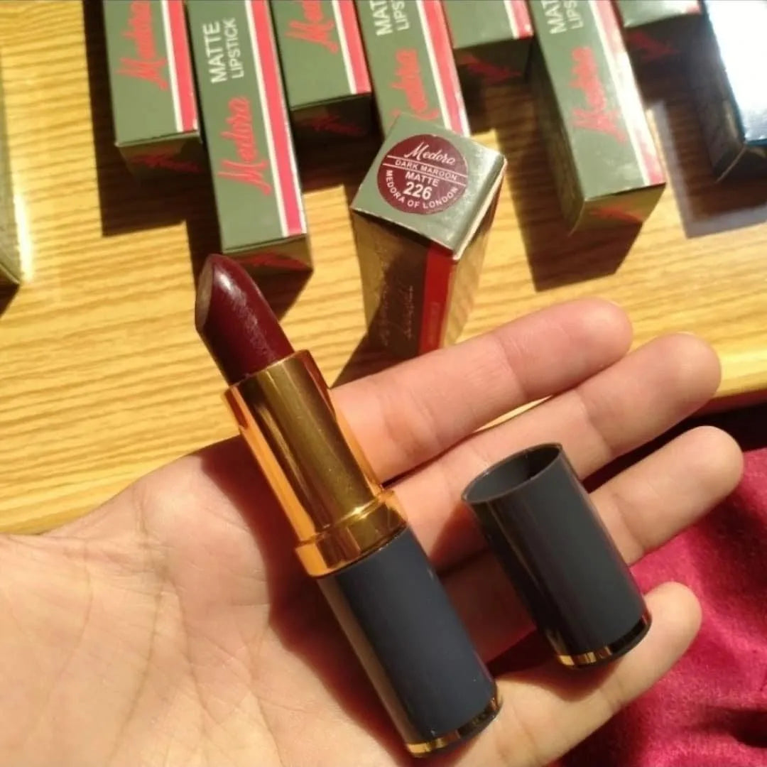 Matte lipstick held in a hand with product packaging in the background
