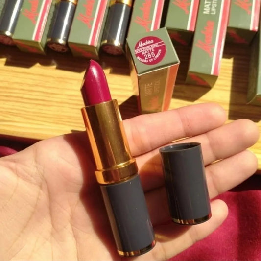 Lipstick held in a hand with product packaging in the background