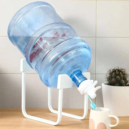 Water dispenser with a large water bottle and a cup on a wooden surface.