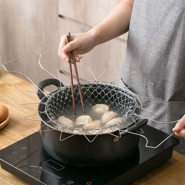 Person using a wire strainer to cook dumplings in a pot on a stove.
