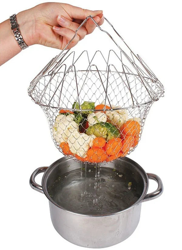 Metal mesh vegetable steamer basket with vegetables being used over a pot of water.