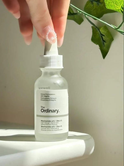 Bottle of 'The Ordinary' serum held by a hand with a light background