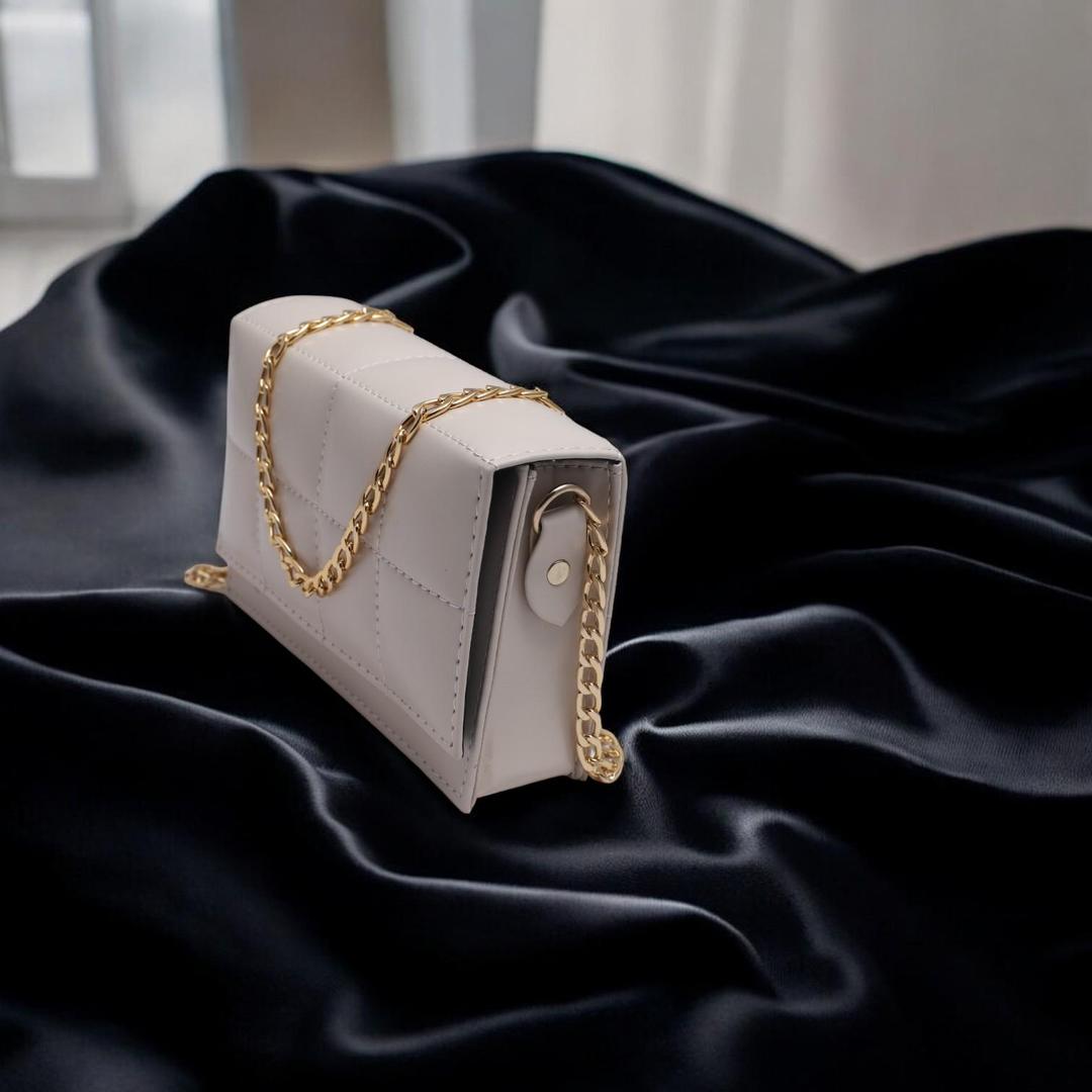 Beige handbag with gold chain on black fabric